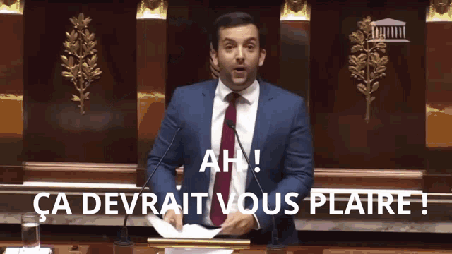 a man in a suit and tie is giving a speech in front of microphones and the words ah ca devrait vous plaire
