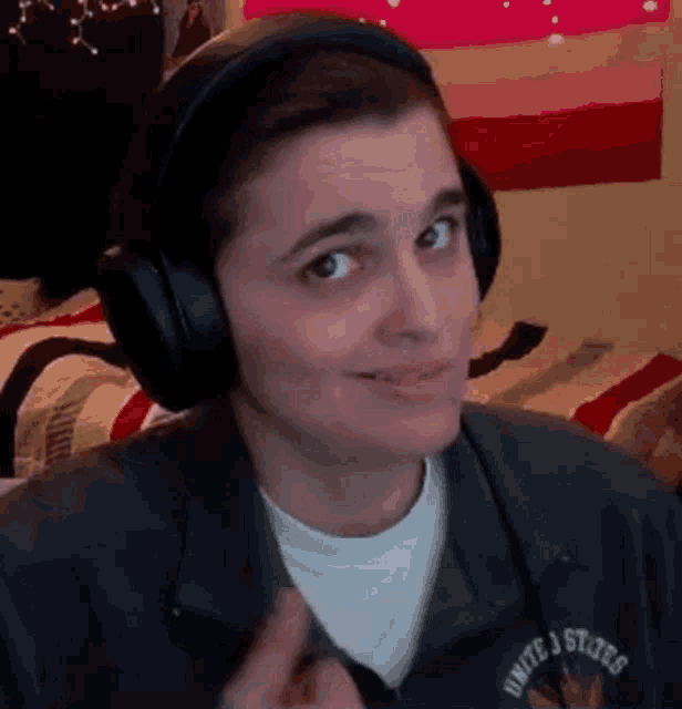 a man wearing headphones is making a funny face while sitting on a bed .