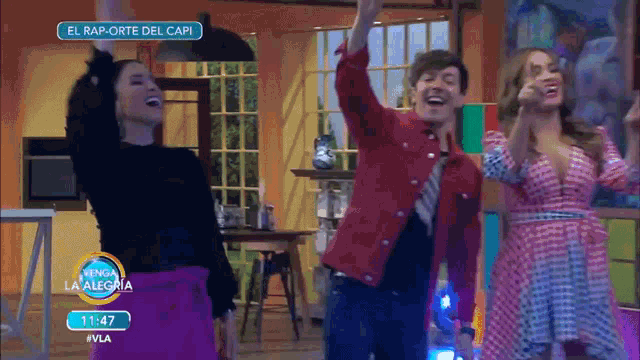 three people are dancing in front of a sign that says el rap-orte del capi