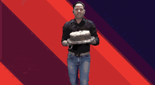 a man in a black shirt is holding a cake in his hand