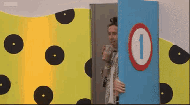 a man holding a cup behind a door with the number one on it
