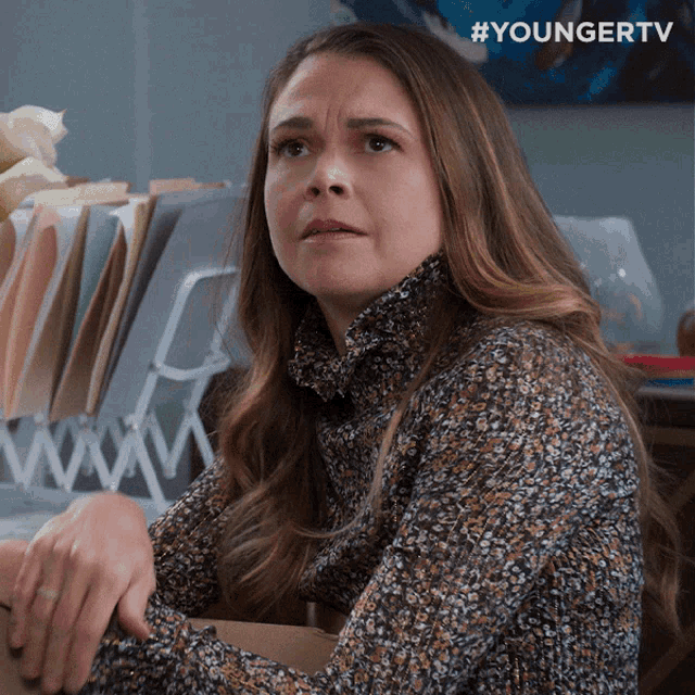 a woman is sitting in front of a filing cabinet and the hashtag #youngertv is above her