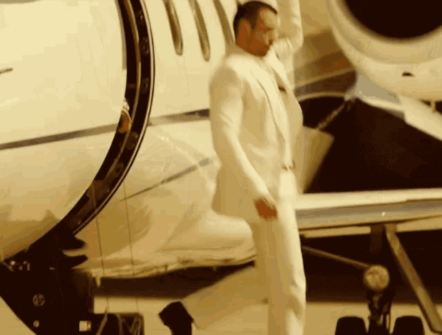 a man in a white suit stands in front of a plane