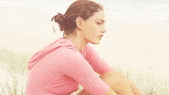 a woman in a pink shirt is sitting on the beach .