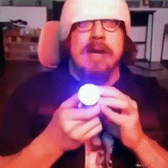 a man wearing glasses and a white hat is holding a light