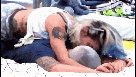 a woman with a tattoo on her arm is laying on a man 's back
