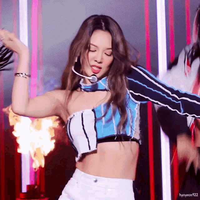 a woman wearing a blue and white crop top is dancing on a stage