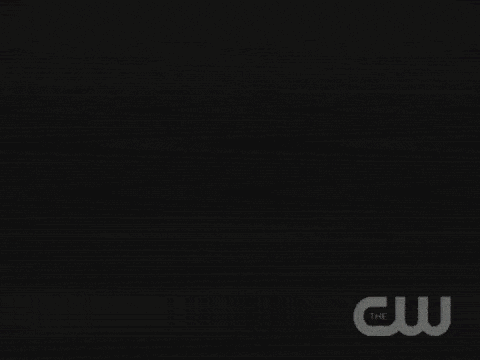 a woman holding a gun in front of a sign that says the cw