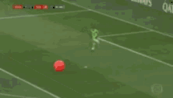a soccer player kicking a red ball on the field