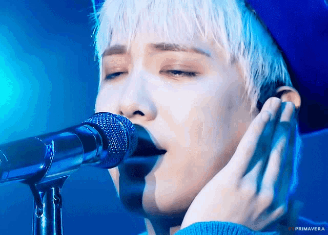 a close up of a person singing into a microphone with the word primavera on the bottom left