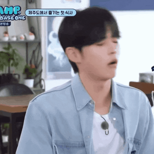 a man wearing a denim shirt and a white t-shirt has a sign above his head that says mr base one