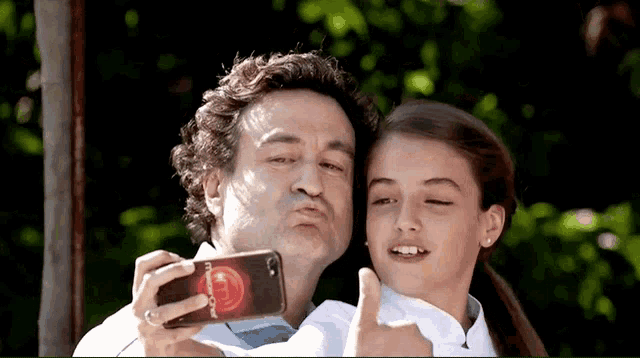 a man and a girl taking a selfie with a phone that says mastercard on it