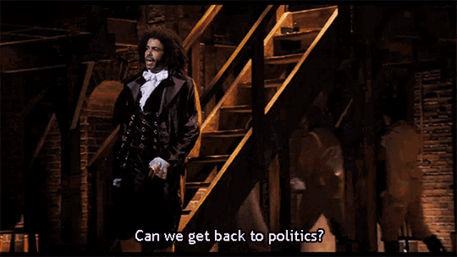 a man in a purple suit says " can we get back to politics " while standing next to another man