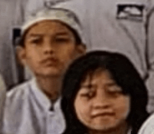 a boy and a girl are sitting next to each other in a group photo .
