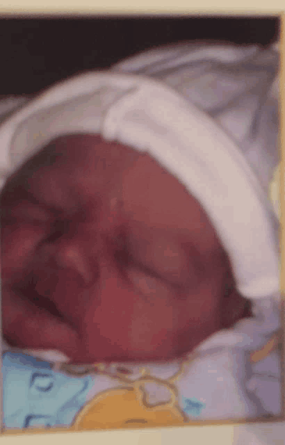 a baby wearing a white hat is sleeping on a blue and yellow blanket
