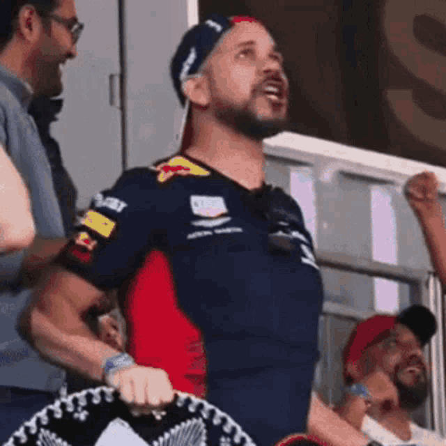 a man wearing a red bull shirt is standing in a crowd