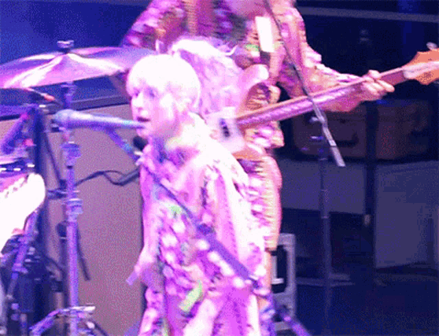 a person playing a guitar in front of a microphone