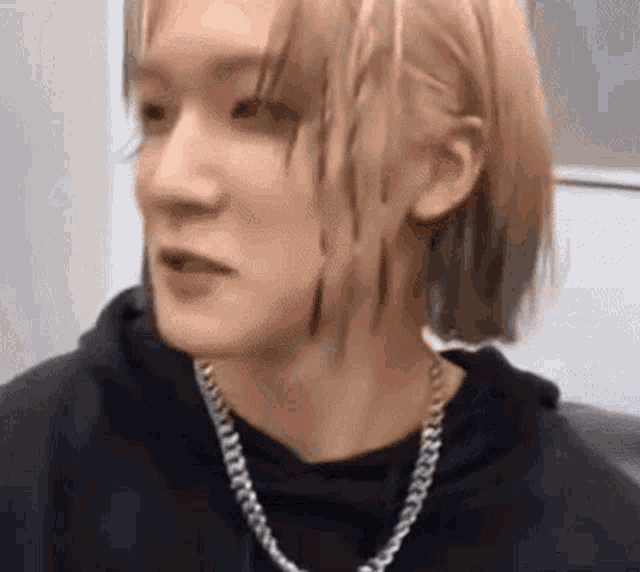 a close up of a person wearing a chain around their neck and a black hoodie .