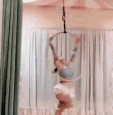 a woman is doing aerial acrobatics in a room with curtains
