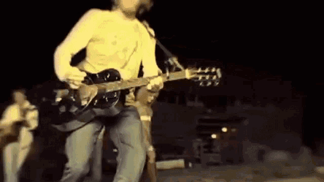 a man is playing a guitar and singing into a microphone while standing on a stage .