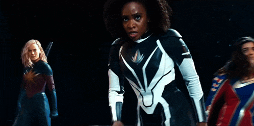 three women in superhero costumes are standing next to each other .