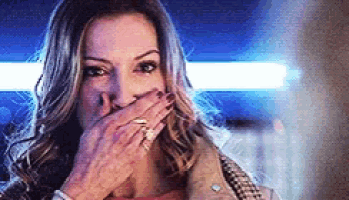 a woman is covering her mouth with her hand while wearing a ring .
