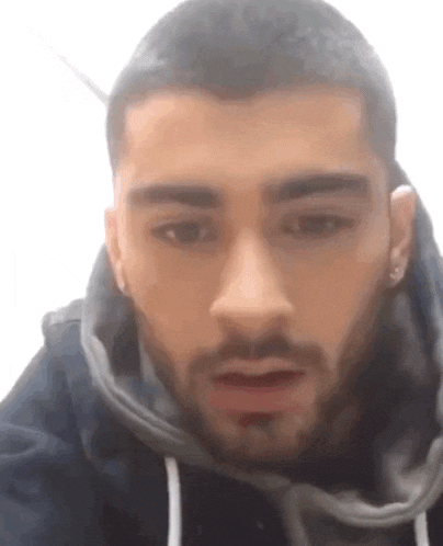 a close up of a man 's face with a beard wearing a black hoodie