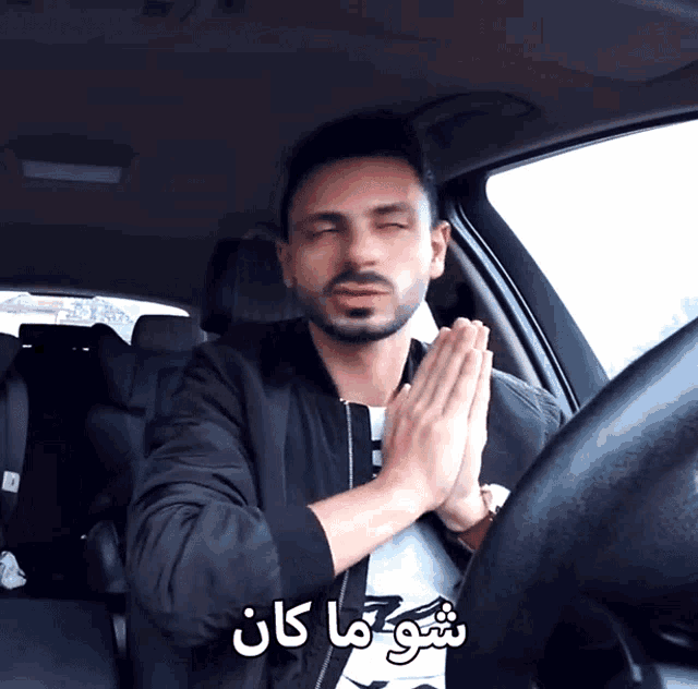 a man sitting in a car with his eyes closed and a foreign language written on the bottom