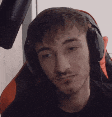 a man wearing headphones and a black shirt looks at the camera