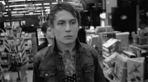 a man in a denim jacket is standing in a store looking at something .