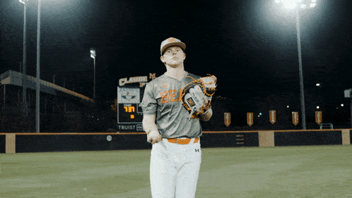 a baseball player stands on a field with a sign that says trust on it
