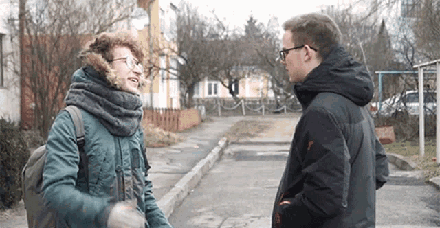two men are standing next to each other on a sidewalk