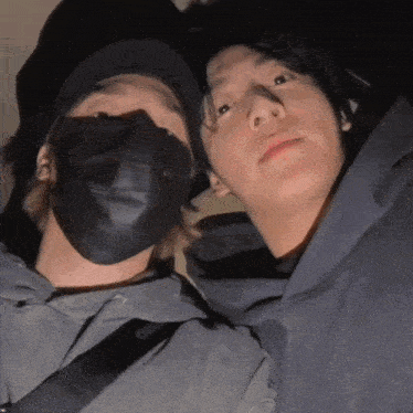 two men wearing face masks are posing for a photo