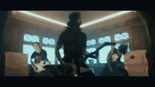 a group of men are playing guitars in a room with a lot of windows