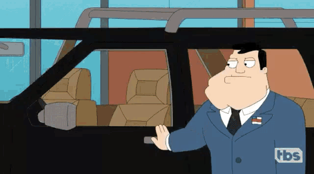 a man in a suit and tie is standing next to a car with a tbs logo on his chest