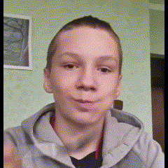 a young boy wearing a gray hoodie is making a funny face