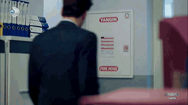 a man in a suit is standing in front of a fire hose box