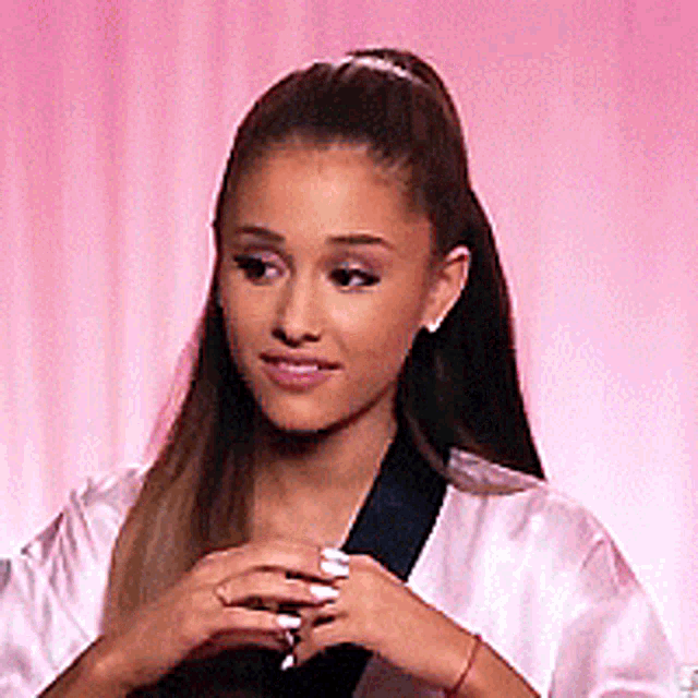 ariana grande is wearing a white robe and holding a ring