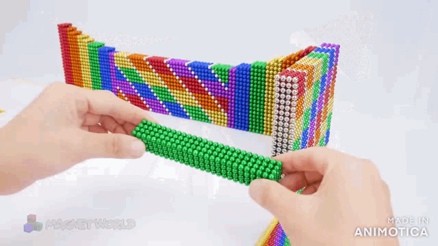 a person is playing with colorful magnets and the words made in animatica can be seen behind them