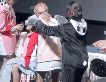 a girl in a black jacket is hugging another girl in a pink jacket