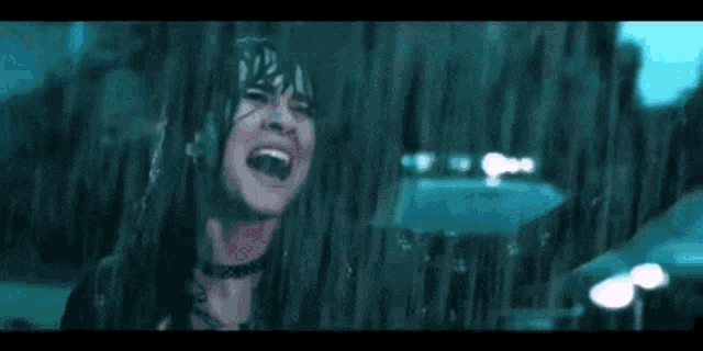 a woman is screaming in the rain while holding an umbrella in front of a police car .