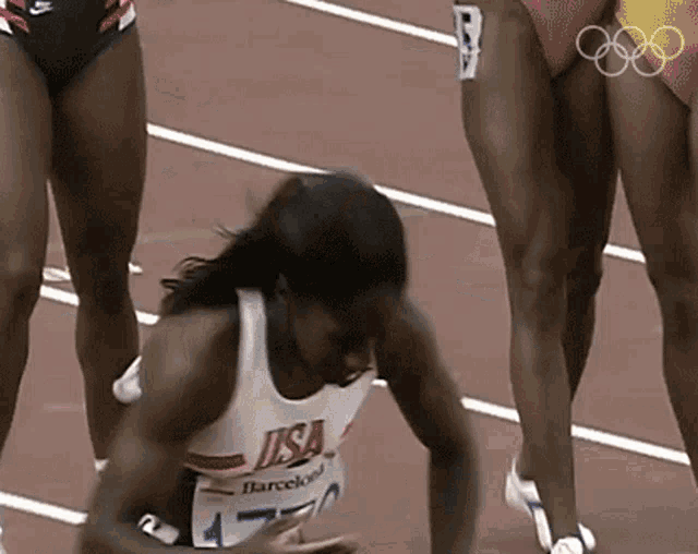 a female runner wearing a usa shirt is laying on the ground