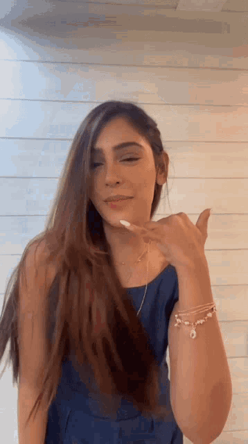 a woman in a blue dress is making a call me sign with her hand