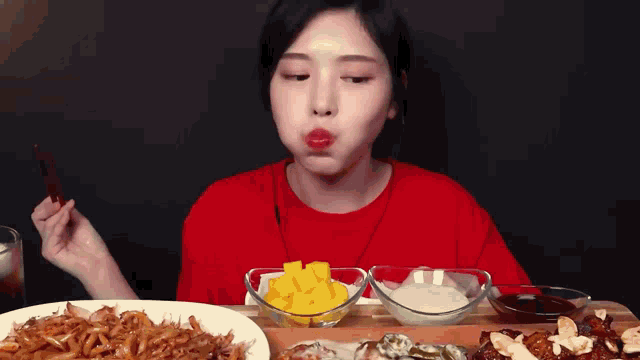 a woman in a red shirt is eating a variety of foods