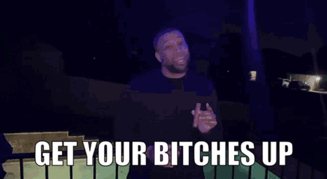 a man is standing on a balcony with the words `` get your bitches up '' .
