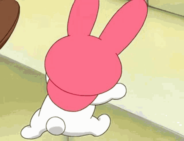 a cartoon rabbit with pink ears is standing on its hind legs on a table .