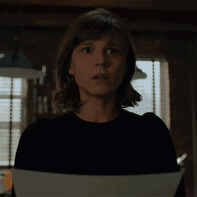 a woman is holding a piece of paper in front of her face