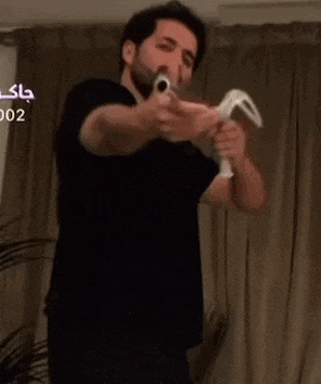 a man in a black shirt is holding a remote control in his hands .