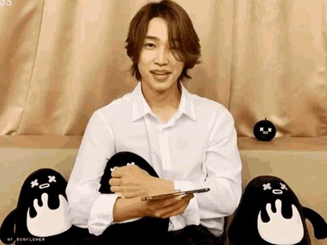 a man in a white shirt is sitting in front of two stuffed penguins .