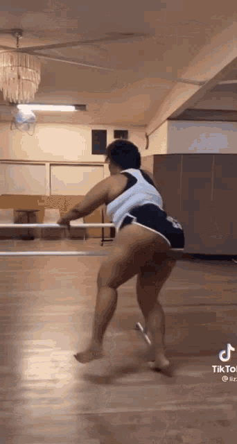 a woman is dancing on a wooden floor in a room .